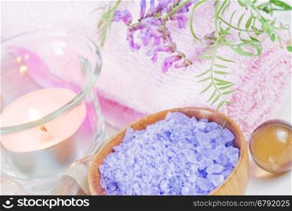 Spa setting with lilac flowers, bath salts and a candle