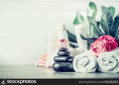 Spa setting with stack of massage stones ,flowers , towels and palm leaves, front view, wellness concept, copy space