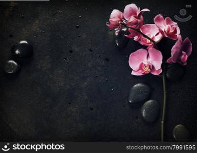 Spa stones and pink orchid on the dark vintage background