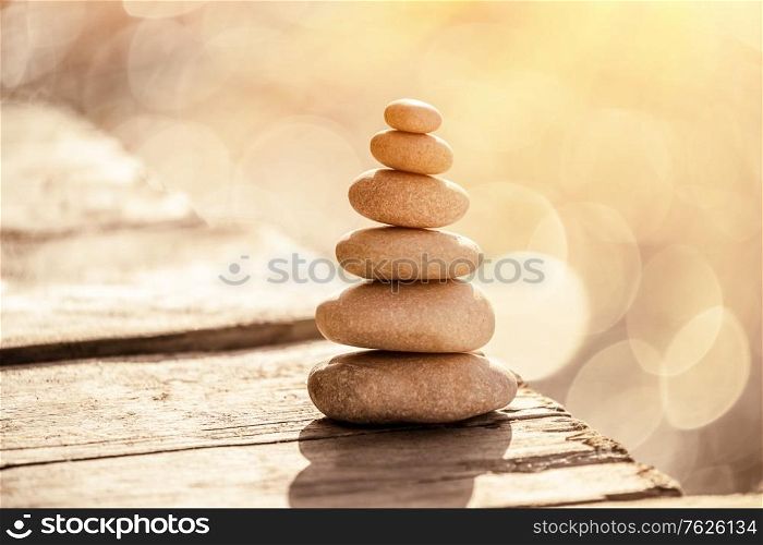 Spa stones still life on the beach, stack of pebbles on the boardwalk over sea in sunset light, peace and relaxation on summer vacation, balance in life concept