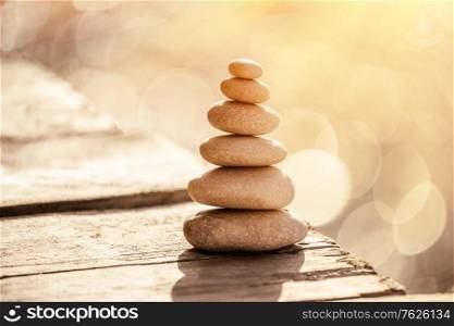 Spa stones still life on the beach, stack of pebbles on the boardwalk over sea in sunset light, peace and relaxation on summer vacation, balance in life concept