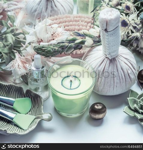Spa treatment with green candle, massage herbal balls and natural wellness tools and products
