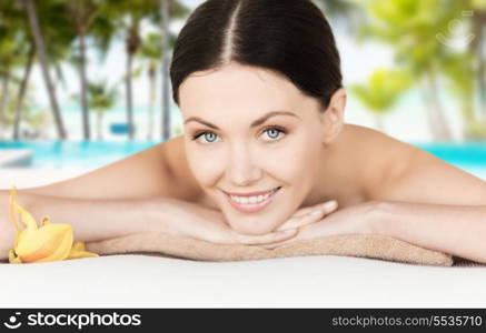 spa, vacation and resort concept - smiling woman in spa salon lying on the massage desk