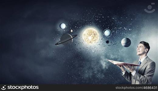 Space exploration. Young businessman with book and planets of space spinning around
