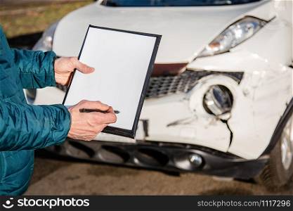 Space for text, blank document close up. An insurance agent will inspect and inspect vehicle damage after an accident. Inspection of the car after an accident on the road.. Space for text, blank document close up. An insurance agent will inspect and inspect vehicle damage after an accident.