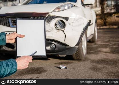 Space for text, blank document close up. An insurance agent will inspect and inspect vehicle damage after an accident. Inspection of the car after an accident on the road.. Space for text, blank document close up. An insurance agent will inspect and inspect vehicle damage after an accident.
