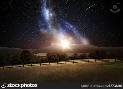space, nature and landscape concept - natural landscape over night sky with shooting stars and galaxy background. landscape over space and stars in night sky
