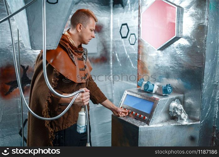 Space scientist holds wires at the control panel in spacecraft with foil walls. Fantasy spaceship for interstellar travel, future science and technology, universe discovery