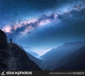 Space with Milky Way, girl and mountains. Silhouette of standing woman on the mountain peak, mountains and starry sky at night in Nepal. Sky with stars. Trekking. Night landscape with bright milky way
