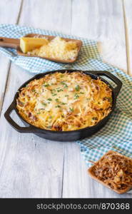 Spaetzle with cheese and fried onion on a white wooden table. German specific pasta dish. Oktoberfest noodle food. Homemade cheese pasta.