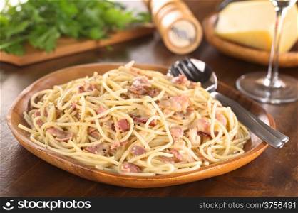 Spaghetti alla Carbonara served on wooden plate (Selective Focus, Focus one third into the meal)