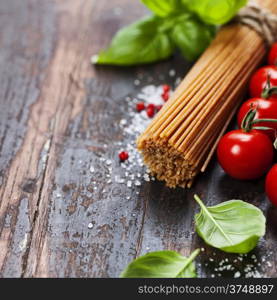 Spaghetti and tomatoes with herbs on an old and vintage wooden table