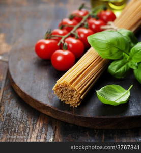 Spaghetti and tomatoes with herbs on an old and vintage wooden table