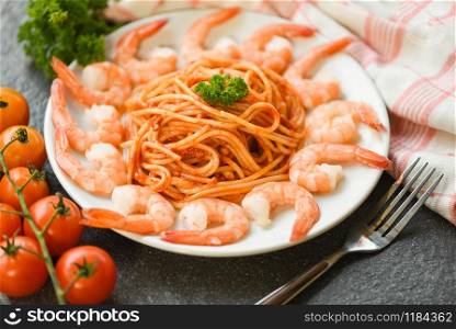 Spaghetti bolognese italian pasta with shrimp prawn served on white plate with tomato parsley in the restaurant italian food and menu concept / spaghetti seafood top view
