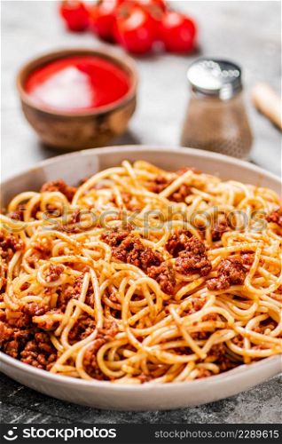 Spaghetti bolognese with cherry tomatoes on the table. On a gray background. High quality photo. Spaghetti bolognese with cherry tomatoes on the table.