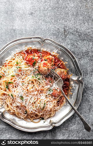 spaghetti bolognese with meatballs in tomato sauce sprinkled with parmesan cheese