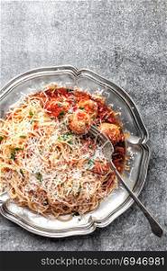 spaghetti bolognese with meatballs in tomato sauce sprinkled with parmesan cheese
