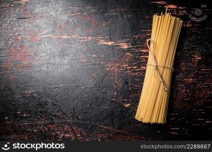 Spaghetti dry tied with a rope. Against a dark background. High quality photo. Spaghetti dry tied with a rope.