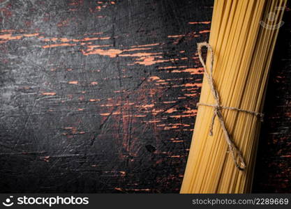 Spaghetti dry tied with a rope. Against a dark background. High quality photo. Spaghetti dry tied with a rope.