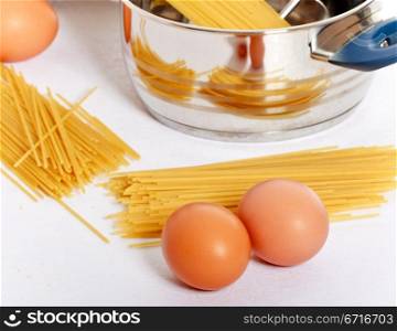 spaghetti, eggs and kitchen utensil on table