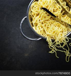 spaghetti in colander on dark vintage background