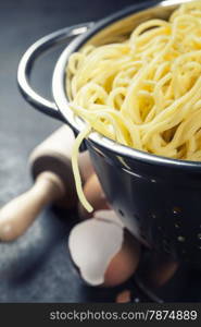 spaghetti in colander on dark vintage background