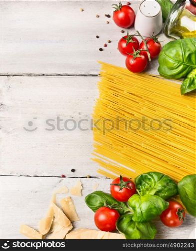 spaghetti ingredients for cooking witj oil,tomatoes and basil on white wooden background, top view,place for text