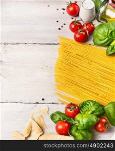 spaghetti ingredients for cooking witj oil,tomatoes and basil on white wooden background, top view,place for text