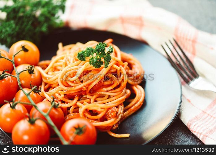 Spaghetti italian pasta served on black plate with tomato and parsley in the restaurant italian food and menu concept / spaghetti bolognese