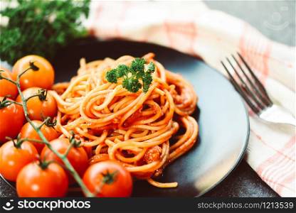 Spaghetti italian pasta served on black plate with tomato and parsley in the restaurant italian food and menu concept / spaghetti bolognese