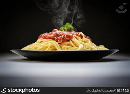 Spaghetti italian pasta served on black plate with tomato sauce and parsley in the restaurant italian food and menu concept / spaghetti bolognese on black background