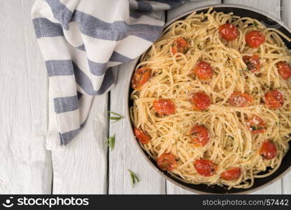 Spaghetti pasta with tomatoes and parsley on wooden table.