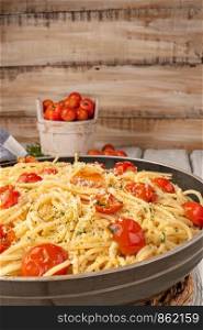 Spaghetti pasta with tomatoes and parsley on wooden table