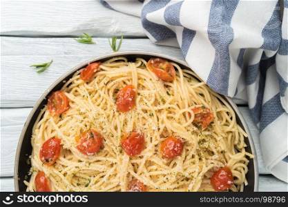 Spaghetti pasta with tomatoes and parsley on wooden table.