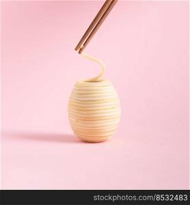 Spaghetti rolled in the shape of Easter eggs and wooden chopsticks isolated on a pink background. Minimal food concept. Square with copy space.. Spaghetti rolled in the shape of Easter egg and wooden chopsticks isolated on a pink background