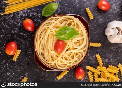 Spaghetti saute in a gray plate with tomatoes and basil