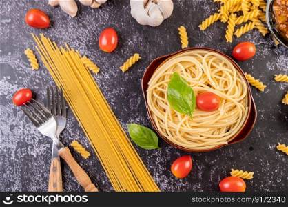 Spaghetti saute in a gray plate with tomatoes and basil