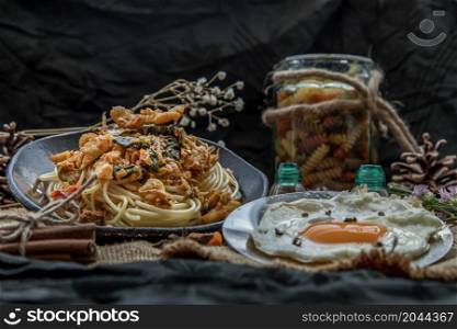 Spaghetti topped with Stir fried spicy snapper on a brown plate Served with Fried Egg. No focus, specifically.