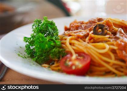 Spaghetti with a tomato sauce on a table in cafe.