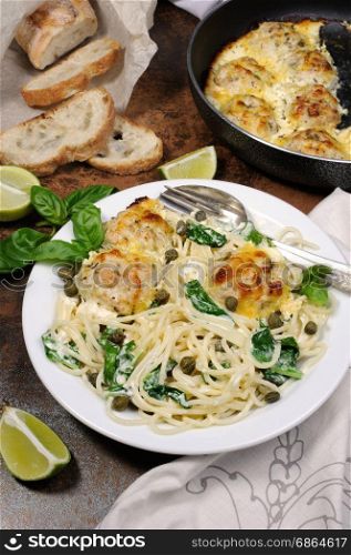 Spaghetti with chicken meatballs in cheese cream sauce , spinach and capers