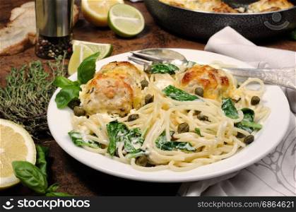 Spaghetti with chicken meatballs in cheese cream sauce , spinach and capers