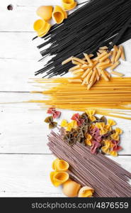 spaghetti with ingredients for cooking pasta. Large selection of uncooked spaghetti and macaroni on the kitchen table with ingredients