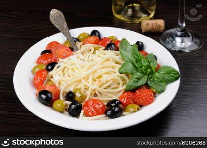 Spaghetti with olives, cherry tomatoes, sprinkled Parmesan and basil