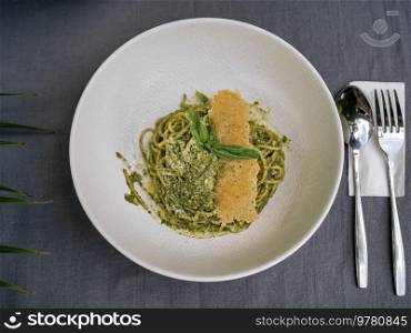 Spaghetti with pesto and coconut under palm tree