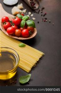Spaghetti with tomatoes in wooden bowl with oil and parmesan cheese with salt on dark brown background. Macro