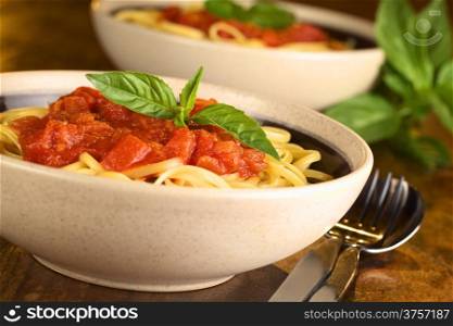 Spaghetti with tomatosauce garnished with a fresh basil leaf (Selective Focus, Focus on the basil leaf in the front)