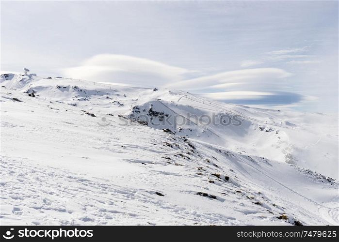 Spain, Andalusia, Granada. Ski resort of Sierra Nevada in winter, full of snow with lenticular clouds in the sky. Travel and sports concepts.. Ski resort of Sierra Nevada in winter, full of snow.