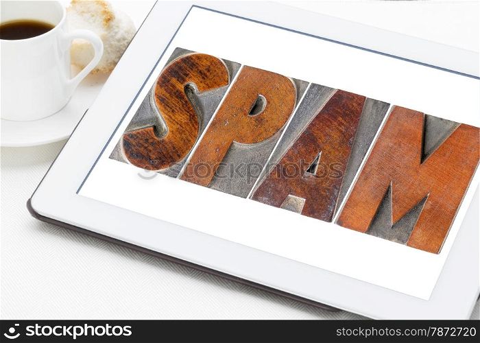 spam word (unsolicited and unwanted commercial email messages) in letterpress wood type on a digital tablet