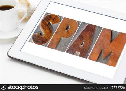 spam word (unsolicited and unwanted commercial email messages) in letterpress wood type on a digital tablet