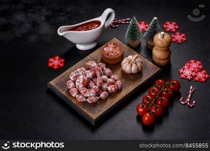 Spanish Fuet sausage slices, on a dark concrete background. Delicious dry sausage with walnuts on a christmas table. Dry cured fuet sausage on a dark background
